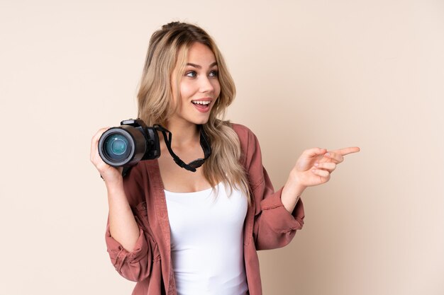 Young photographer girl over wall pointing finger to the side
