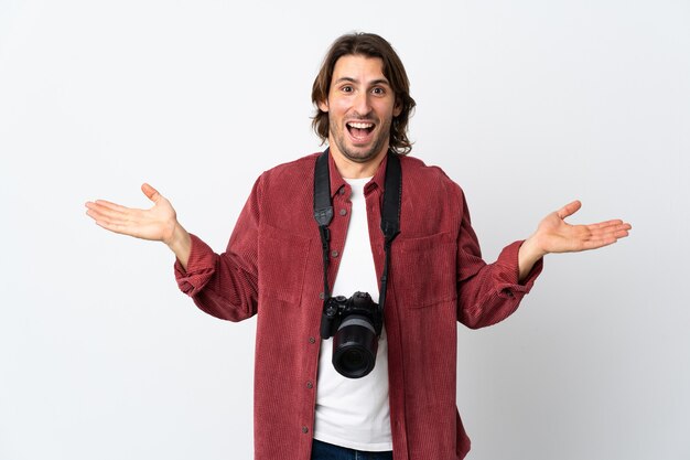 Young photographer man isolated on white wall with shocked facial expression