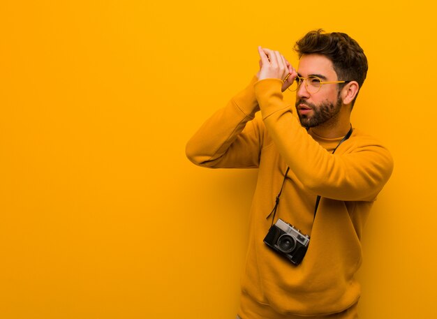 スパイグラスのジェスチャーを作る若い写真家の男