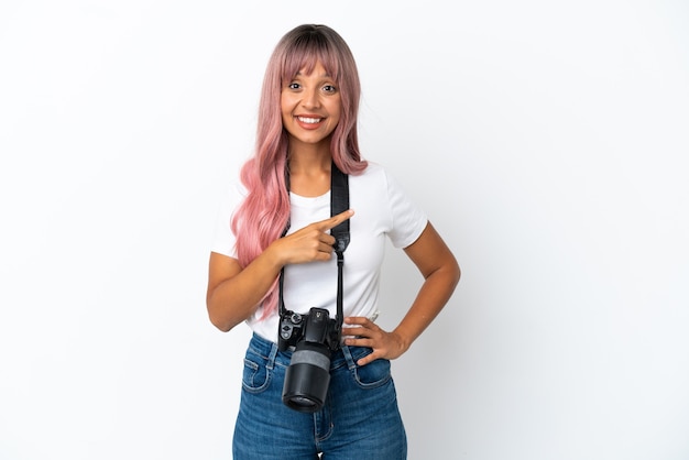 Young photographer mixed race woman with pink hair isolated on white background pointing to the side to present a product