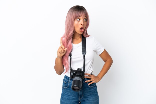 Young photographer mixed race woman with pink hair isolated on white background thinking an idea pointing the finger up