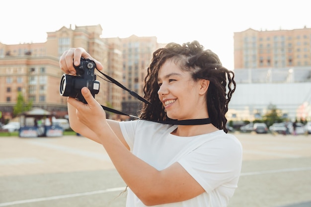 전문 야외 카메라를 가진 젊은 사진가가 문자를 위한 공간으로 향취를 가진 소녀가 도시 풍경 사진을 찍는다