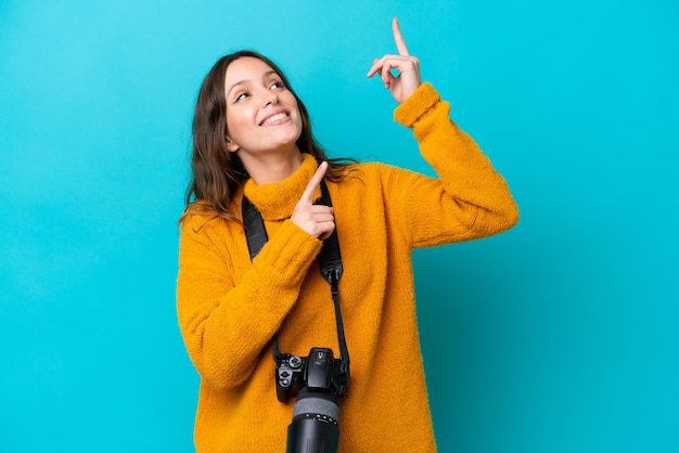 Молодая женщина-фотограф, изолированная на синем фоне, указывая указательным пальцем на отличную идею
