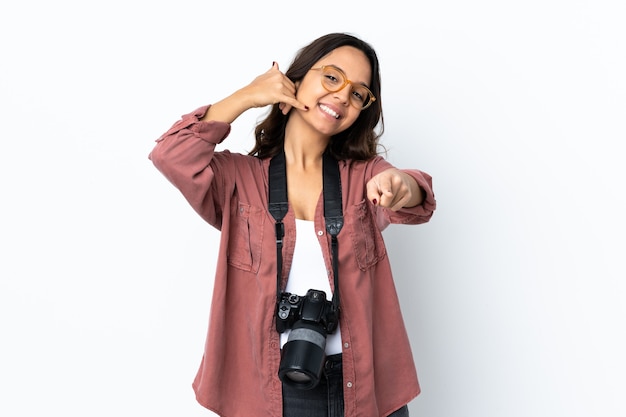 電話のジェスチャーをし、正面を指す孤立した白い背景の上の若い写真家の女性