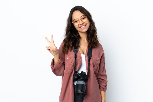 Young photographer woman over isolated white background smiling and showing victory sign