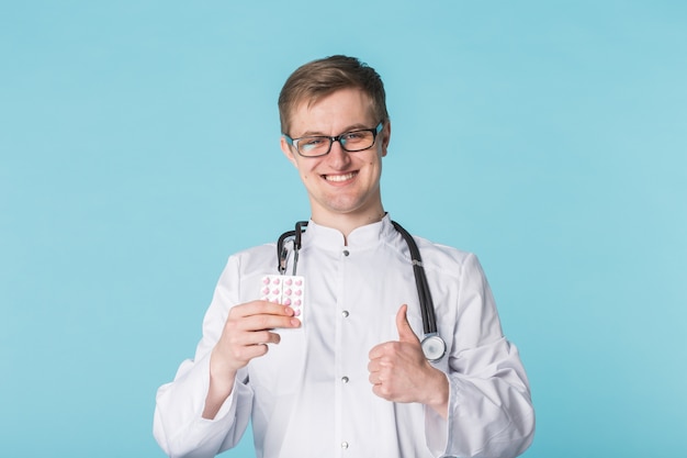 Young physician holding pills.