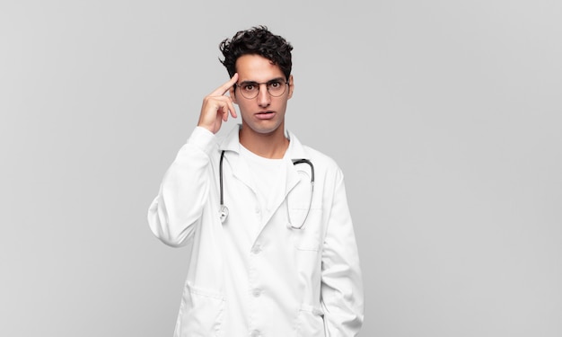 Young physician looking surprised, open-mouthed, shocked, realizing a new thought, idea or concept