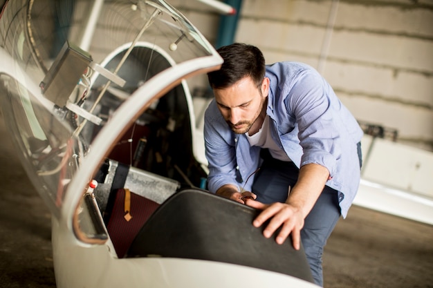 Giovane pilota che controlla l'aeroplano nell'hangar