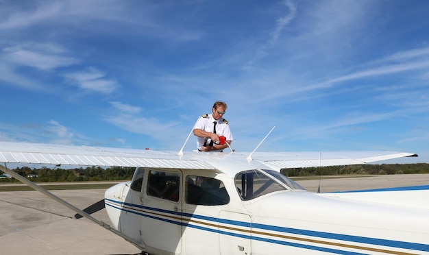 Young pilot filling up the airplane fuel tank on blue sky background