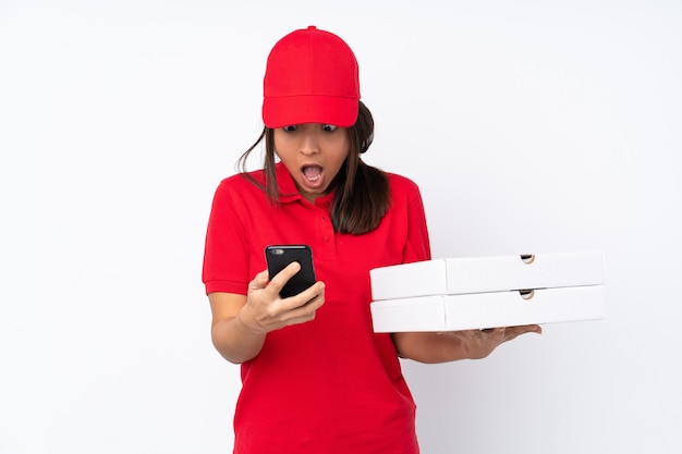 Young Pizza delivery girl over isolated white background surprised and sending a message