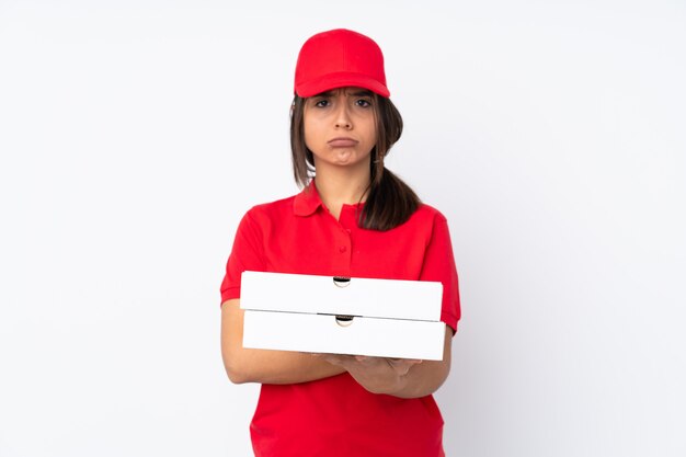 Young Pizza delivery girl over isolated white wall feeling upset