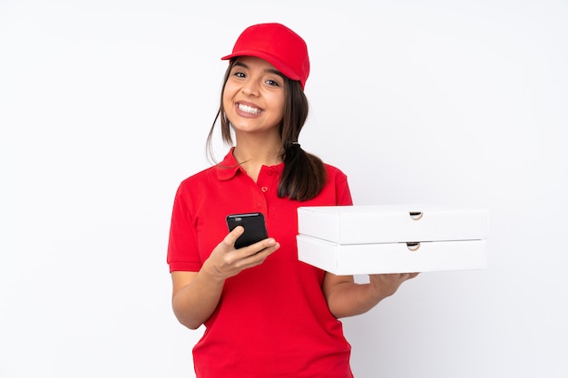 Молодая девушка с доставкой пиццы через изолированную белую стену отправляет сообщение с мобильного