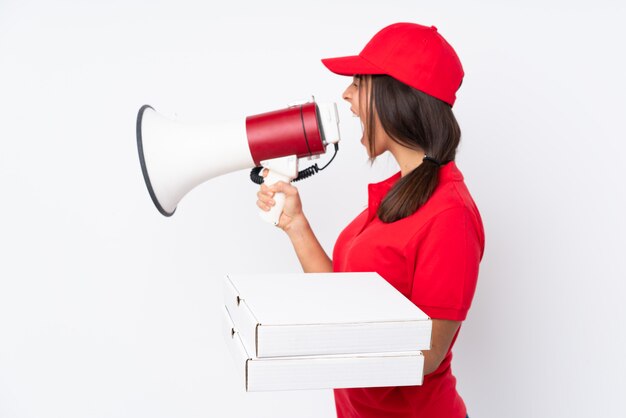 Young pizza delivery girl over isolated white wall shouting through a megaphone