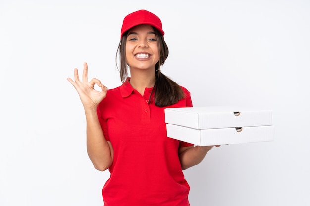 Young Pizza delivery girl over isolated white wall showing an ok sign with fingers