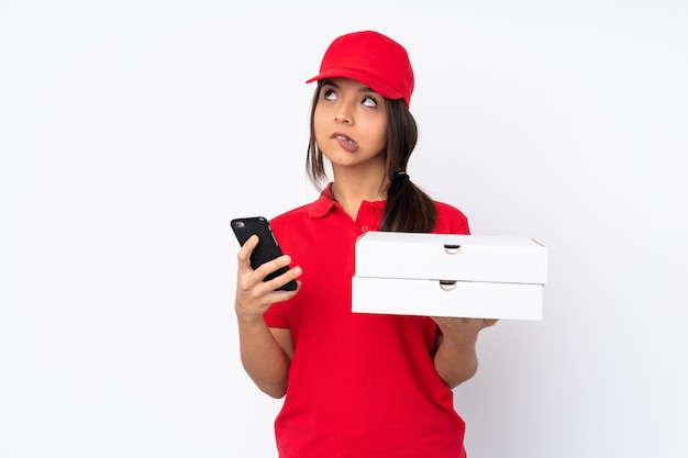 Молодая женщина доставки пиццы держит кофе на вынос и мобильный, думая что-то