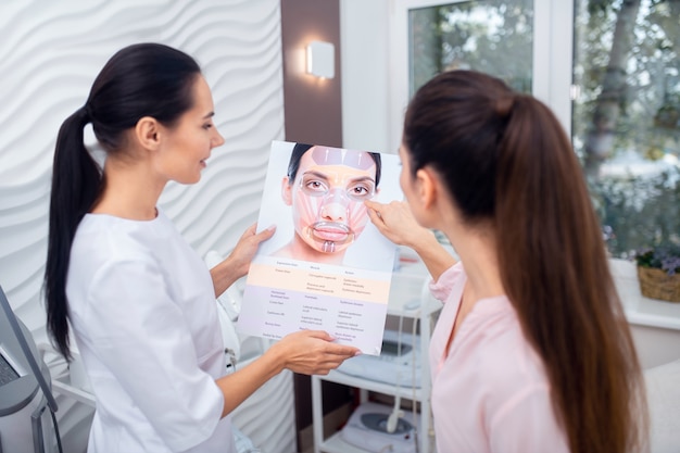 Young plastic surgeon with a patient at the clinic