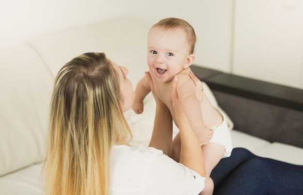 Giovane madre giocosa che gioca con il suo bambino in camera da letto