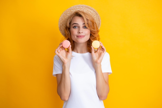 Young pleased woman isolated over yellow background eating macaroons girl eat french macarons