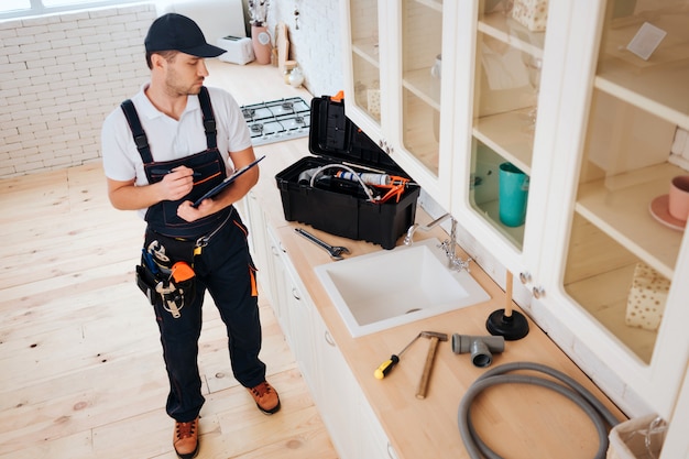 young plumber stand in kitchen at sink