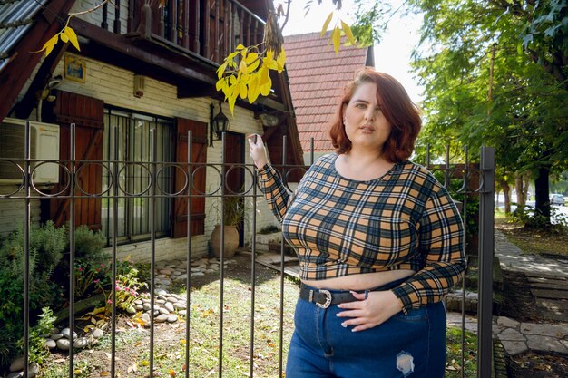 Young plus size argentinian woman standing outside the house looking at the camera