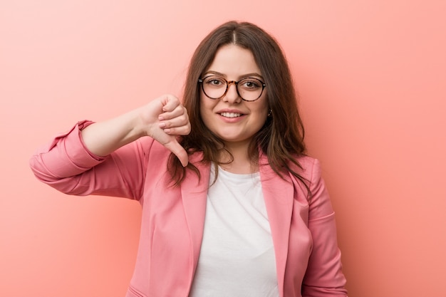 Young plus size business caucasian woman showing a dislike gesture, thumbs down. Disagreement concept.