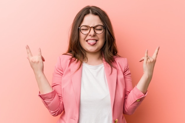 Young plus size business caucasian woman showing rock gesture with fingers