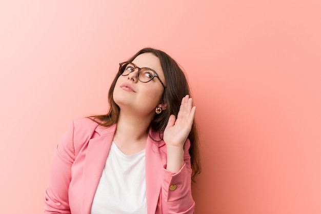 Young plus size business caucasian woman trying to listening a gossip.