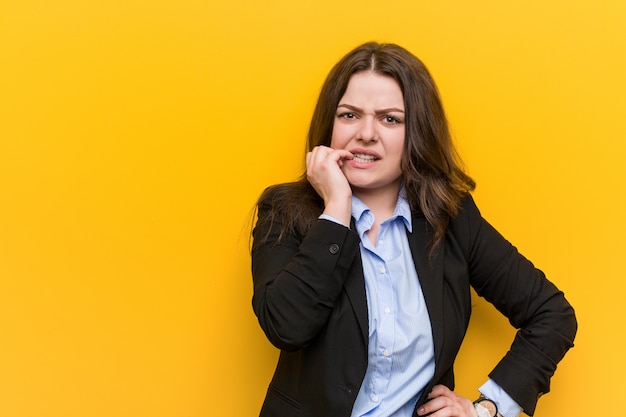 Young plus size caucasian business woman biting fingernails, nervous and very anxious.