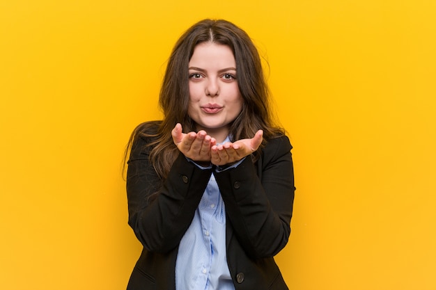 Young plus size caucasian business woman folding lips and holding palms to send air kiss.