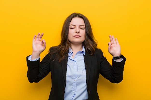 Young plus size caucasica donna d'affari si rilassa dopo una dura giornata di lavoro, sta eseguendo yoga.