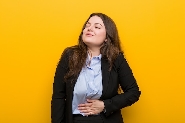 Young plus size caucasian business woman touches tummy, smiles gently, eating and satisfaction concept.