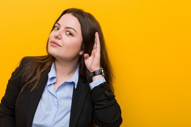 Young plus size caucasian business woman trying to listening a gossip.