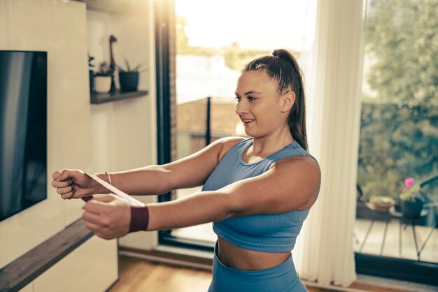 朝、自宅でゴムバンドでトレーニングを行う若いプラスサイズの女性。