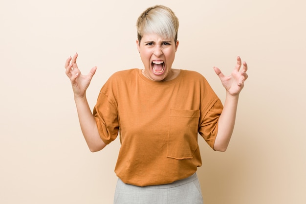 Donna giovane plus size con i capelli corti che grida di rabbia.