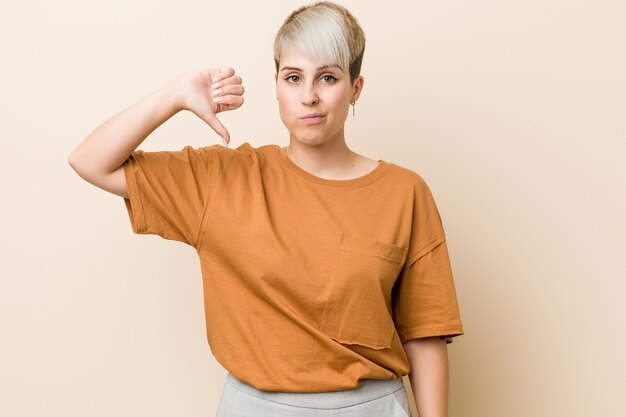 Young plus size woman with short hair showing a dislike gesture, thumbs down. Disagreement concept.