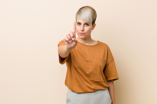 Young plus size woman with short hair showing number one with finger.