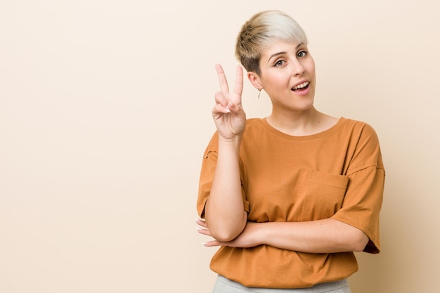 Young plus size woman with short hair showing number two with fingers.