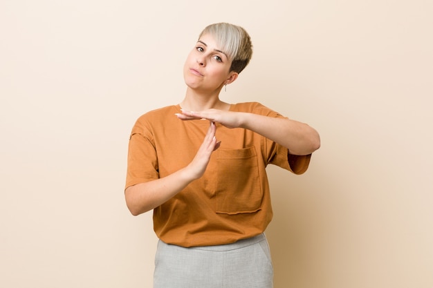Young plus size woman with short hair showing a timeout gesture.