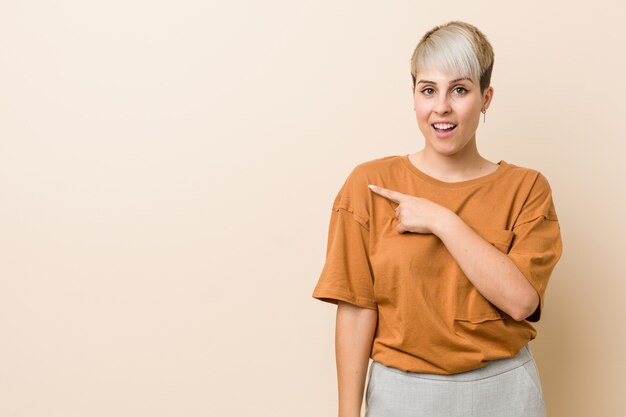 Young plus size woman with short hair smiling and pointing aside, showing something at blank space.