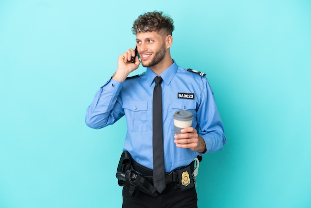 若い警察のブロンドの男は、持ち帰り用のコーヒーと携帯電話を保持している青い背景に白を分離しました