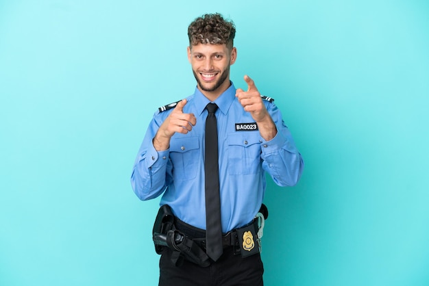 Young police blonde man isolated white on blue background points finger at you while smiling