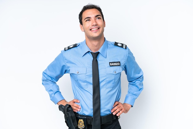 Young police caucasian man isolated on white background posing with arms at hip and smiling