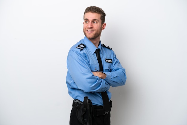 Young police caucasian man isolated on white background with arms crossed and happy