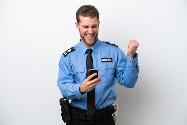 Young police caucasian man isolated on white background with\
phone in victory position