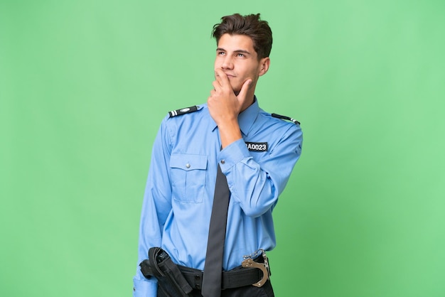 Young police man over isolated background having doubts and with confuse face expression