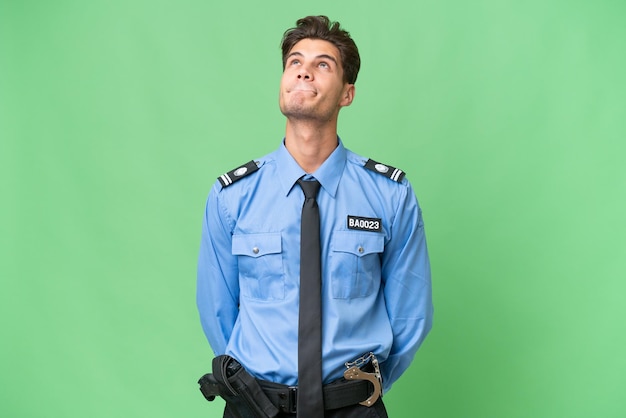 Young police man over isolated background and looking up