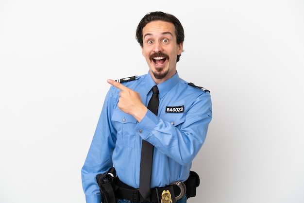 Young police man over isolated background white surprised and pointing side