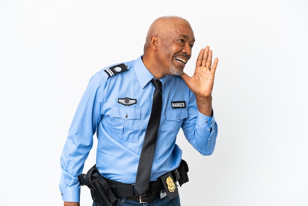 Young police man isolated on white background shouting with mouth wide open to the side