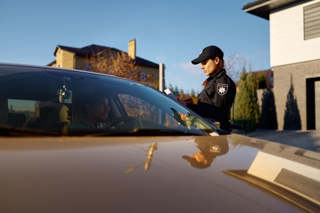 Young policewoman with tablet standing near car. traffic police\
woman work on road