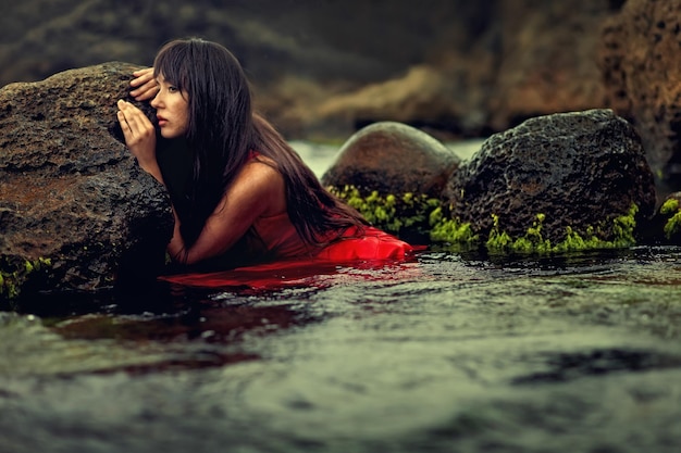 Young posing by rock in water